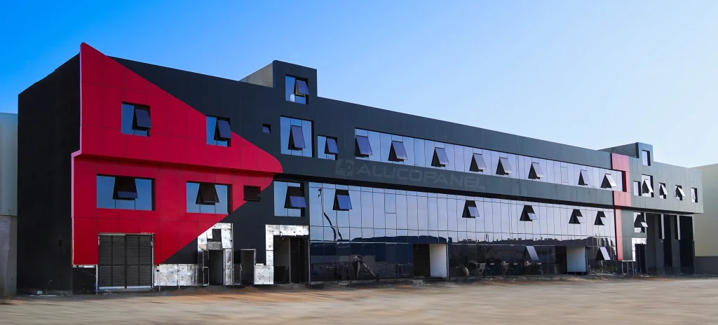 Full facade of commercial building clad in ALUCOPANEL® red and black aluminium composite panels with reflective glass curtain wall in UAE