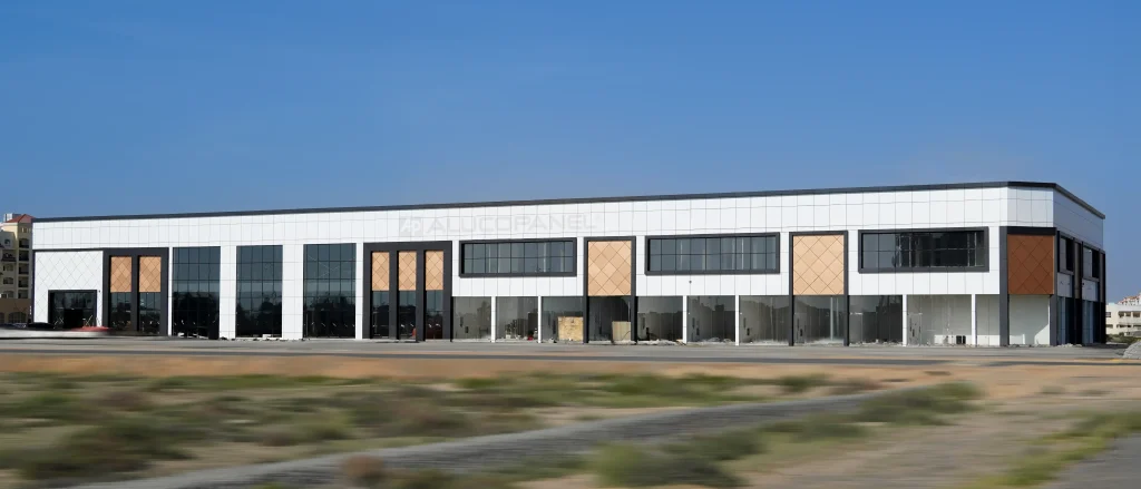 Full front elevation of retail strip building with ALUCOPANEL® white composite cladding and copper diamond accent panels under blue sky in UAE