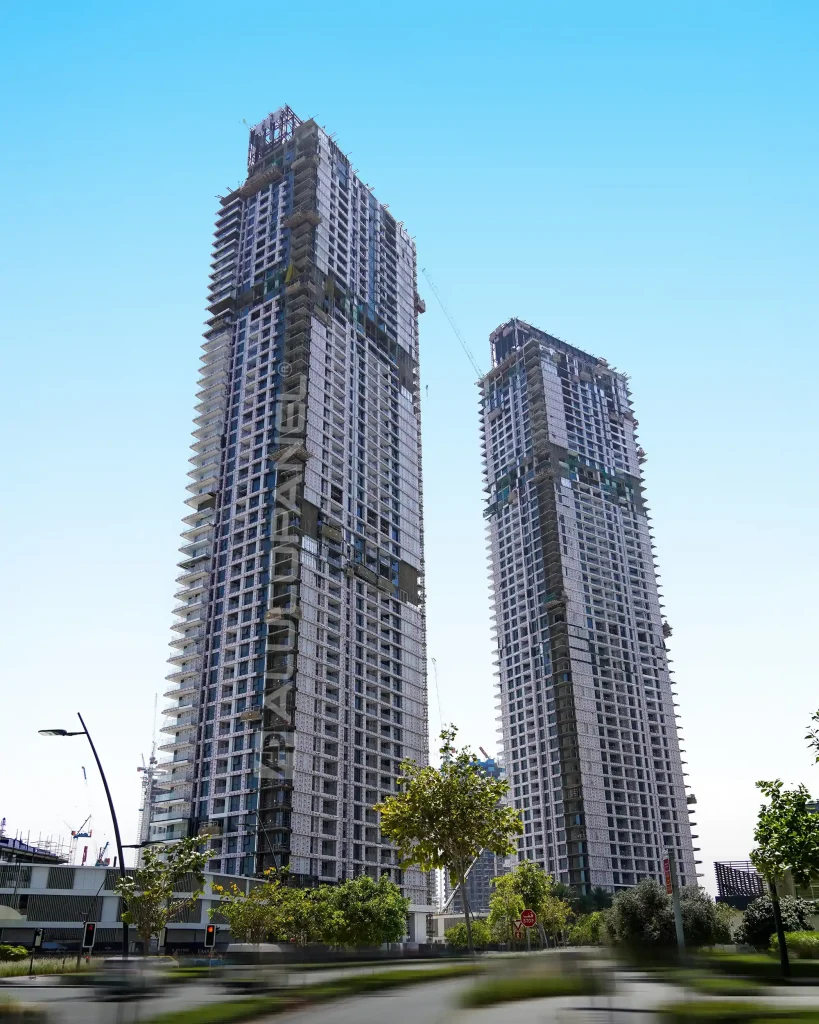 Aerial street view of Creek Waters twin residential towers under construction in Dubai Creek Harbour, UAE, clad with ALUCOPANEL® façade panels against a clear blue sky