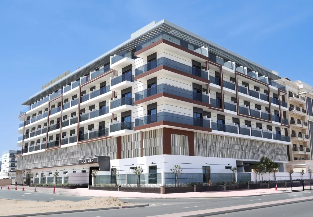 Corner view of L'Olivier completed residential building with ALUCOPANEL® wood-effect and white cladding, balconies, and vertical louvre screen in Dubai
