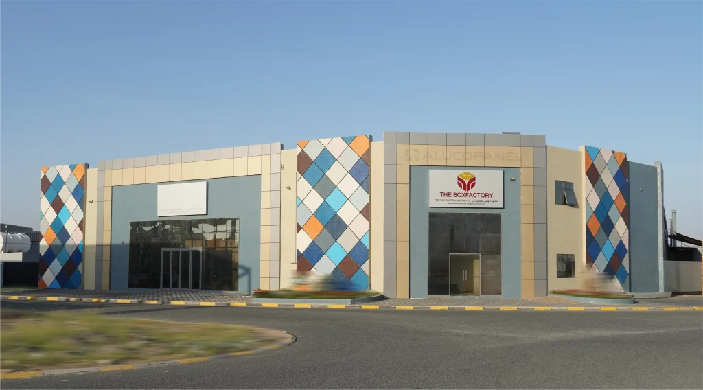 Full facade of The Box Factory building featuring ALUCOPANEL® multicolour diamond-pattern composite cladding in blue, orange, brown and white with beige panels in UAE
